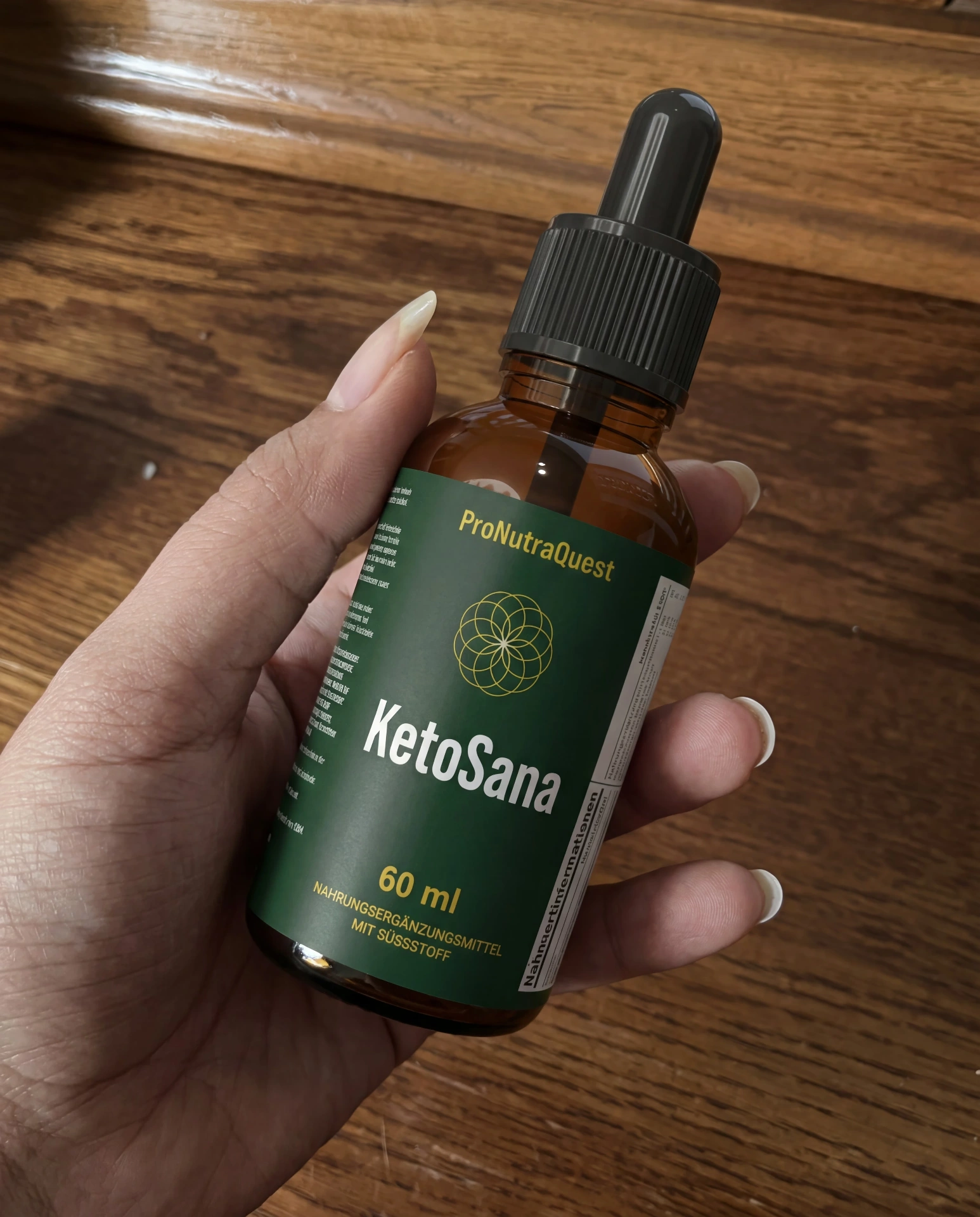 KetoSana in der Hand auf Holzhintergrund